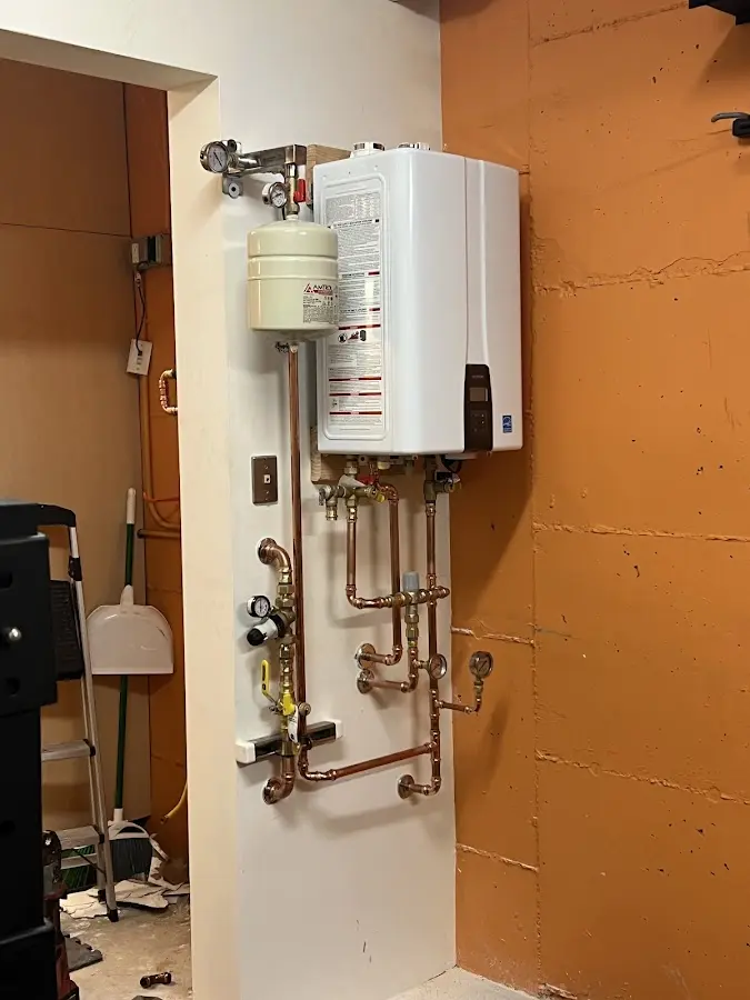 Plumbing technician inspecting water heater connections in Hazlehurst